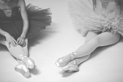 Low section of women wearing tutu sitting on white background