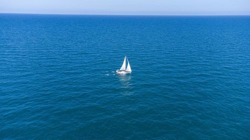 Sailboat sailing in sea against blue sky