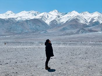 Rear view of woman standing on snow covered mountains