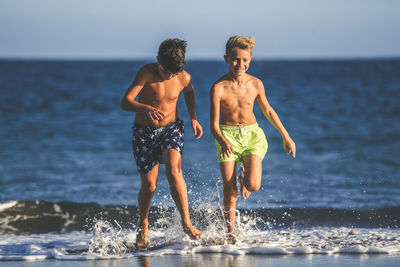 Full length of shirtless boy on sea shore