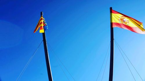 Low angle view of flags against clear blue sky