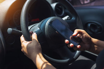 Midsection of person holding camera in car