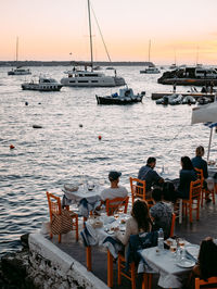 People sitting on chair by sea against sky