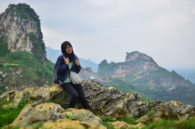 Man sitting on rock against mountains