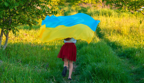 Rear view of woman walking on grassy field