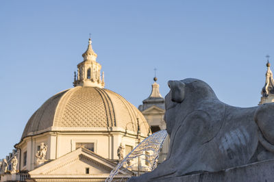Low angle view of fountain lion statue against church and sky