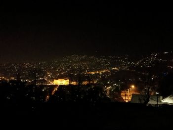 Illuminated cityscape against sky at night