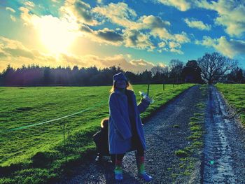 Rear view of woman on field against sky during sunset