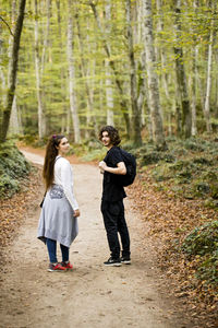 Portrait of couple standing on dirt road in forest