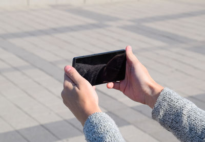 Cropped image of woman using mobile phone outdoors