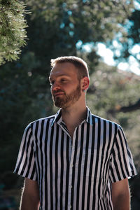 Man wearing striped shirt against trees