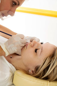 Close-up of young woman applying medicine at home