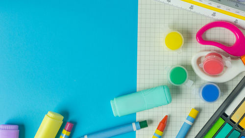 High angle view of colorful school supplies over blue background