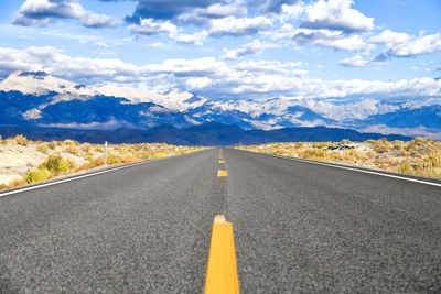 Surface level of road heading towards mountains against sky