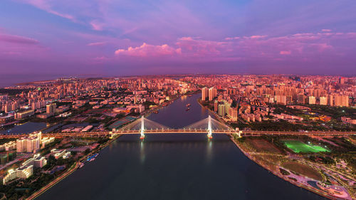 High angle view of illuminated buildings by river against sky