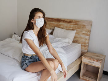 Young woman sitting on bed at home