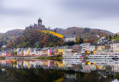 Buildings by river against sky