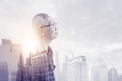 Digital composite image of man looking at cityscape against sky
