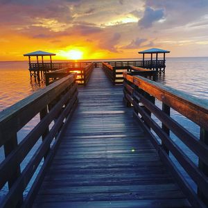 Pier over sea against sky during sunset