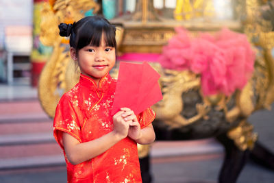 Close-up of cute girl holding red flowers