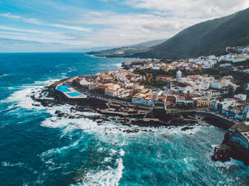 Aerial view of sea and buildings against sky