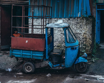 Side view of abandoned car on street against building