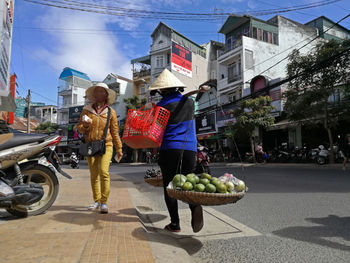 People walking on road by buildings in city