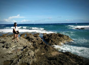 Full length of woman on rock looking at sea