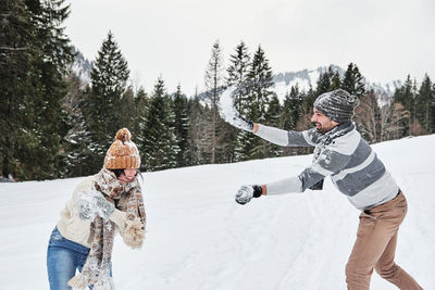 Young couple in winter sweaters having a snowball fight outdoors. snow, happy, fun.