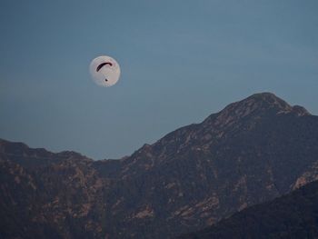 Low angle view of kite in mountains against clear sky