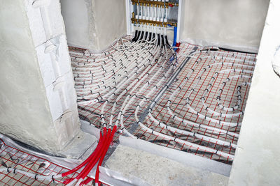 White pipes of underfloor heating systems, arranged in foil, passing through the foundation.