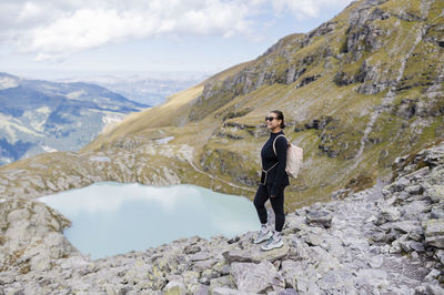 Happy hiker with backpack standing on rock