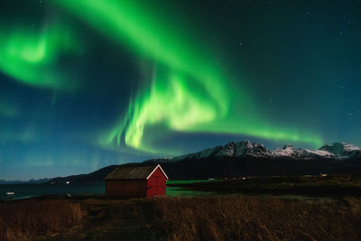 Scenic view of building against snowcapped mountains and northern lights at night