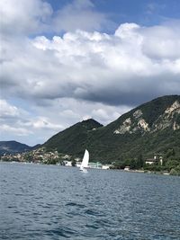 Sailboat on sea by mountains against sky