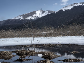 Scenic view of frozen lake by mountains against sky