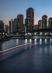 Buildings by river against sky in city