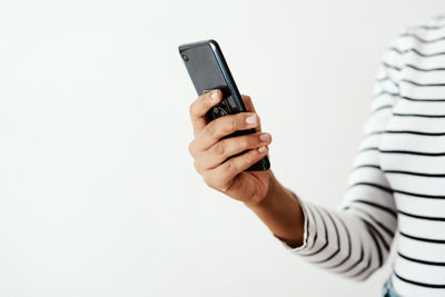 Midsection of woman using mobile phone against white background