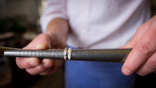 Midsection of person holding metal in workshop