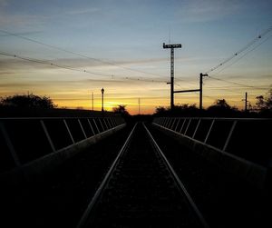 Railroad tracks against sky during sunset