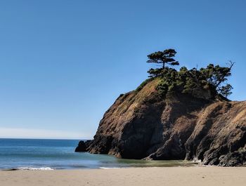 Rock formation on beach against clear blue sky