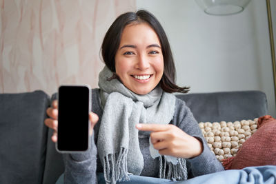 Portrait of young woman using mobile phone at home