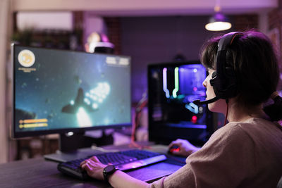 Rear view of woman using laptop at home