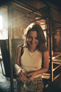 Young woman smiling while standing against building