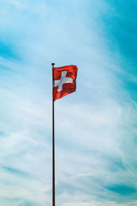 Low angle view of swiss flag against blue sky