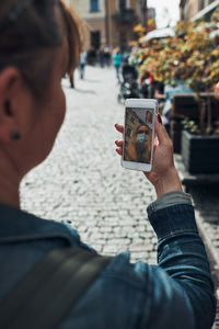 Rear view of woman talking on video call standing outdoors