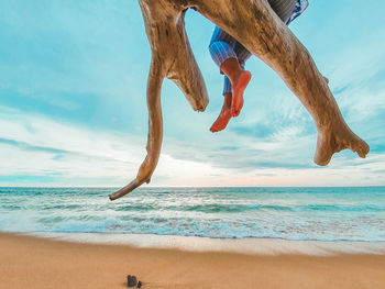 Low section of people on beach against sky