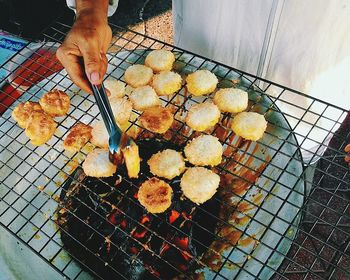 Cropped image of man preparing food on metal grate