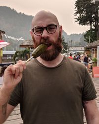 Portrait of young man eating food while standing outdoors