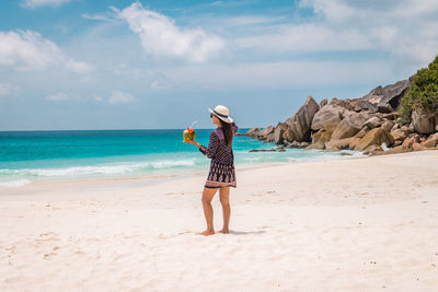 Woman standing at beach against sky