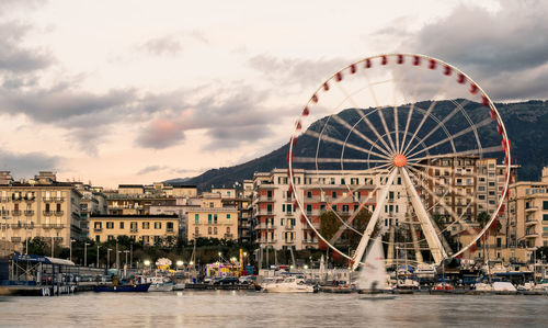 Ferris wheel in city against cloudy sky